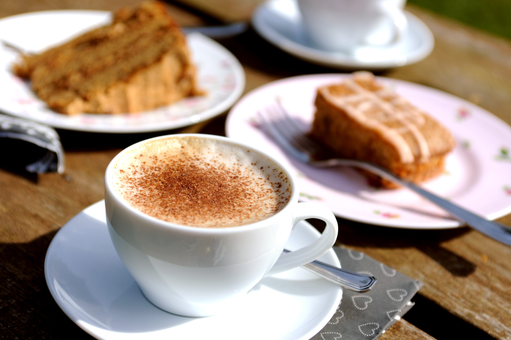wooden table with plates of cake and a mug of coffee